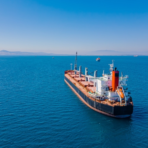 An aerial view of a bulk vessel for dry cargo in anchorage in sea waiting loading in industrial port