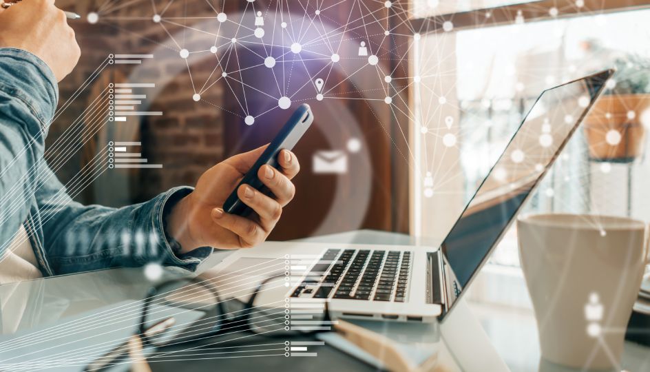 Male hands using smartphone and laptop on the desk working remotely